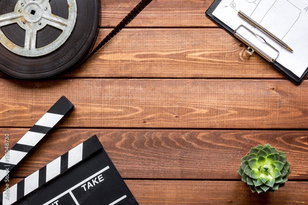 Screenwriter desktop with movie clapper board wooden background top view