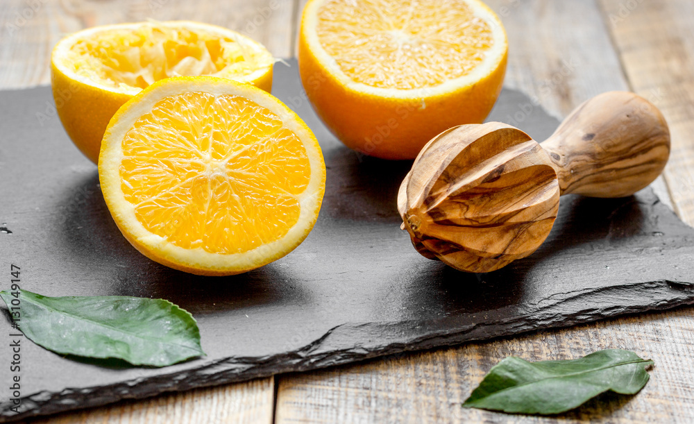 cut oranges in half and juicer on wooden background