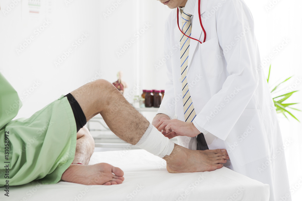 The doctor is wrapping a bandage on the mans foot