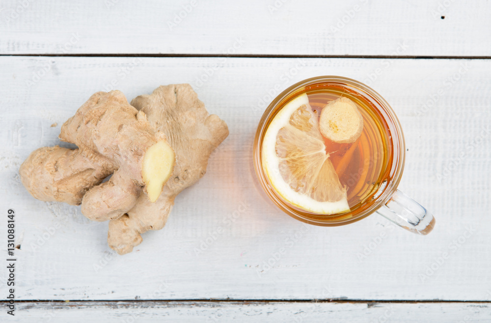 Ginger tea in a glass cup on wooden background