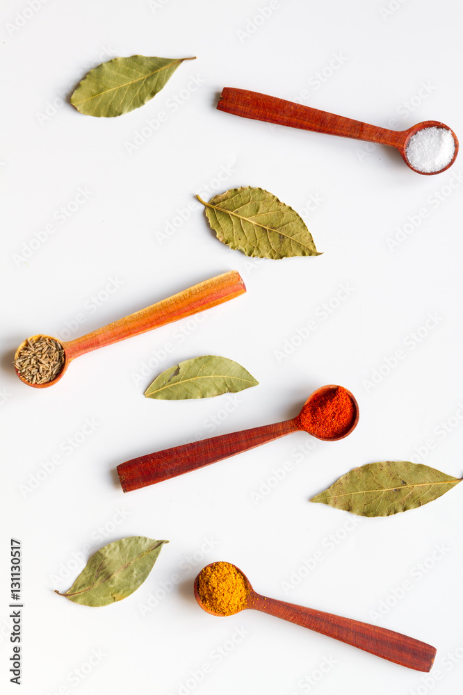 spices in wooden spoons on white background top view