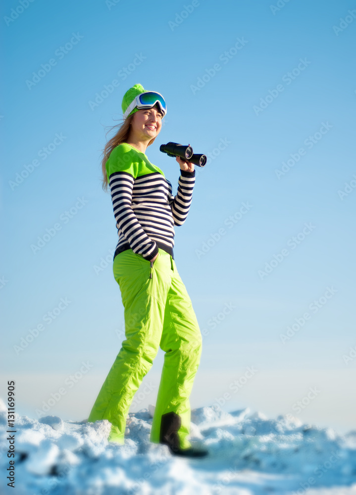 happy girl in a ski suit and mask with binoculars in hand