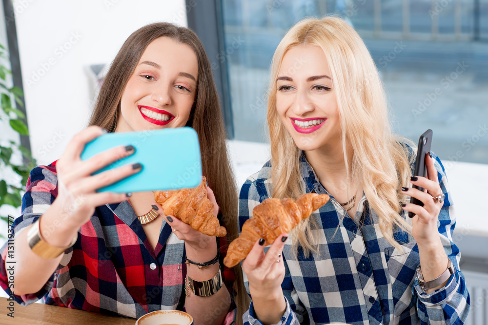 Young female friends dressed casually in checkered shirts taking selfie photo with coffee cups and c