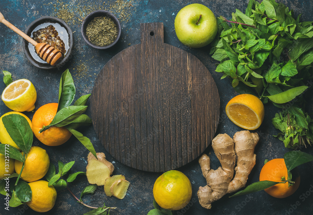 Ingredients for making natural hot drink with wooden board in center. Oranges, mint, lemons, ginger,