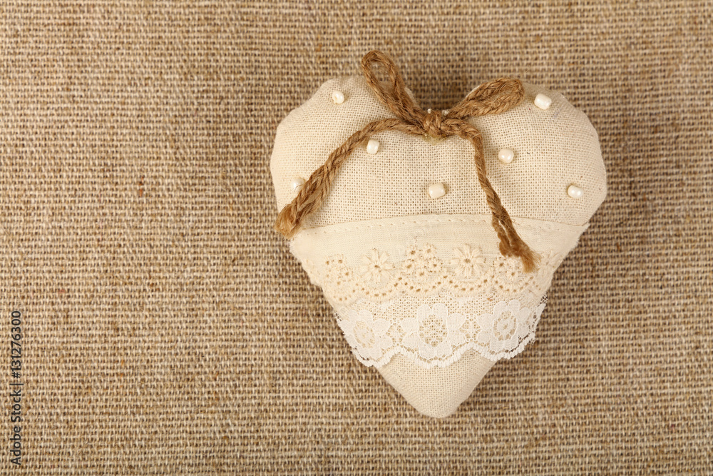 White beige toy heart with lace and bow on canvas