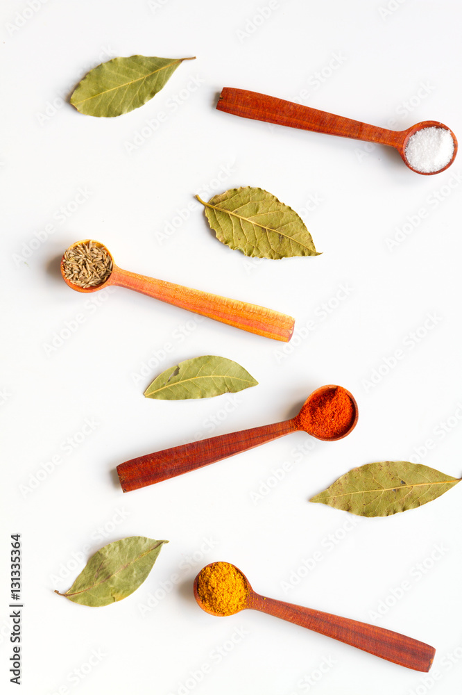 spices in wooden spoons on white background top view