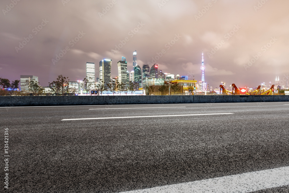 Asphalt road and modern cityscape at night in Shanghai