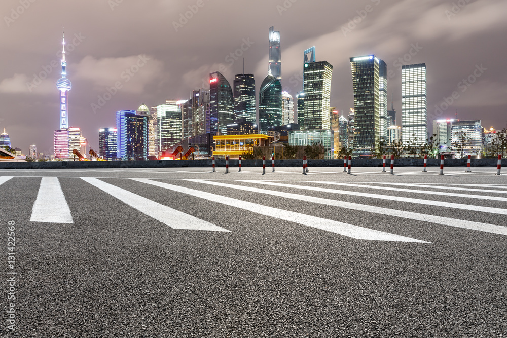 Asphalt road and modern cityscape at night in Shanghai