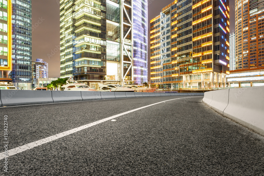 Asphalt road and modern cityscape at night in Shanghai