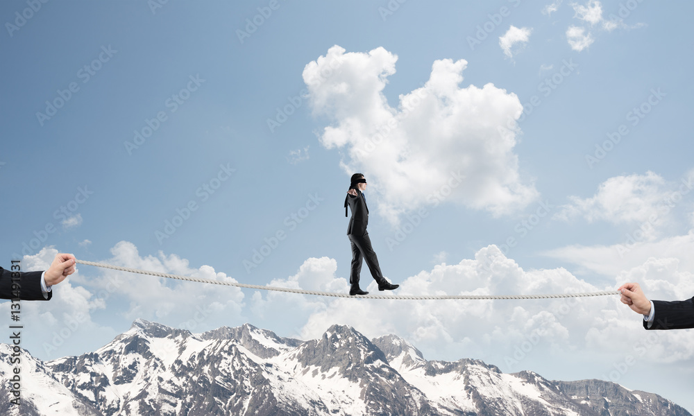 Business concept of risk support and assistance with man balancing on rope