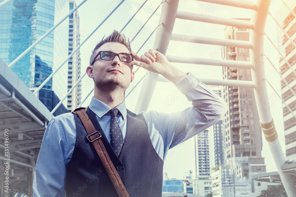 Confident smart handsome business man in a stylish suit standing with folded arms on a rooftop of n 