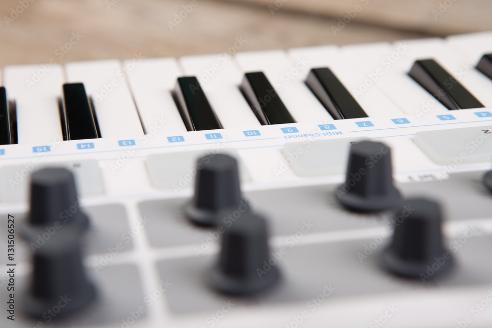 Close up of MIDI controller volume fader, knob and keys.