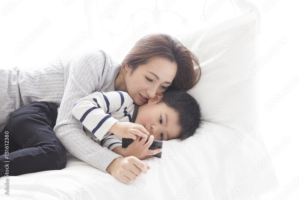 Mother and son are watching smartphone in bedroom