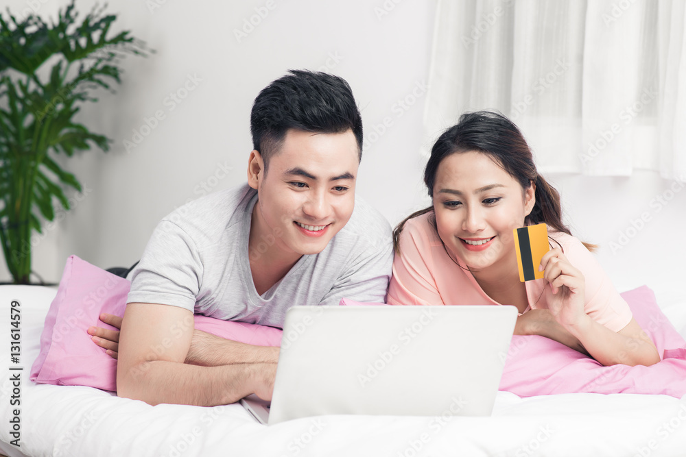 Young asian couple surfing on internet and shopping with laptop