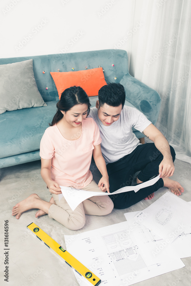 Attractive young asian adult couple looking at house plans.