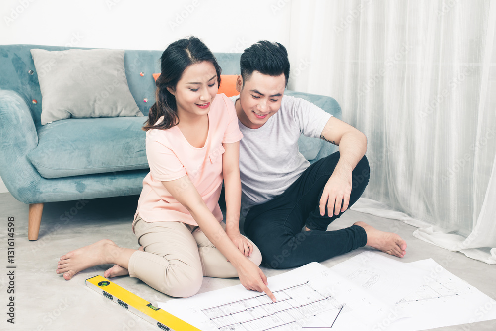 Attractive young asian adult couple looking at house plans.