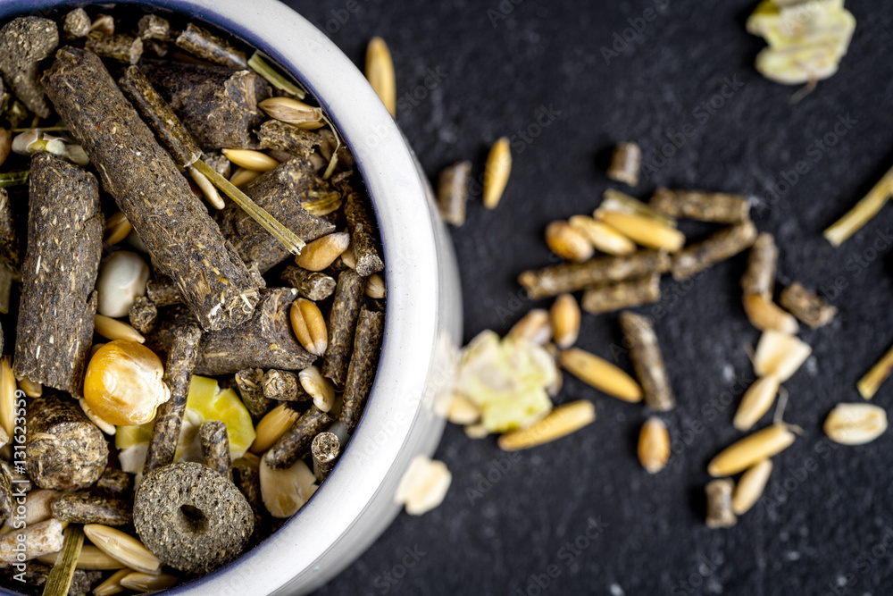 dry food for rodents in bowl dark background top view