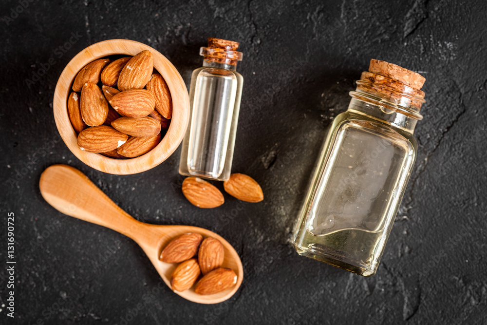 cosmetic almond oil in glass bottle on dark background