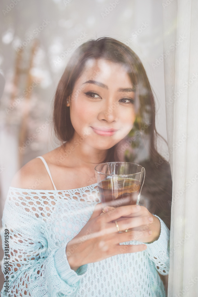 Portrait of a gorgeous young asian woman relaxing with cup of ho