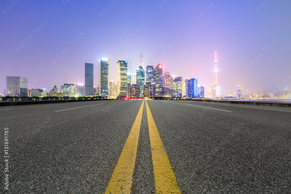 Asphalt road and modern cityscape at night in Shanghai