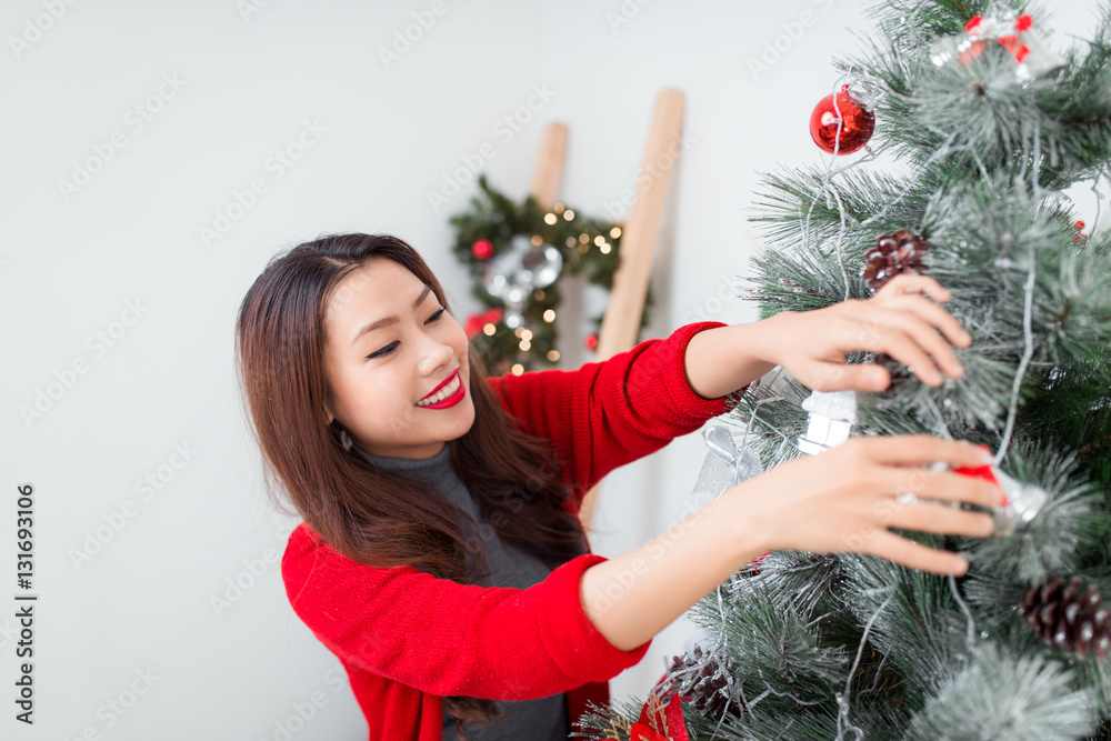 Happy young asian woman  standing near christmas tree at home ce