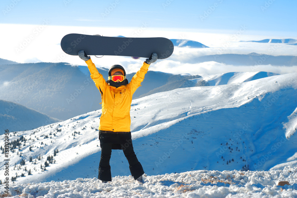 女孩在冬季群山的全景下举起滑雪板