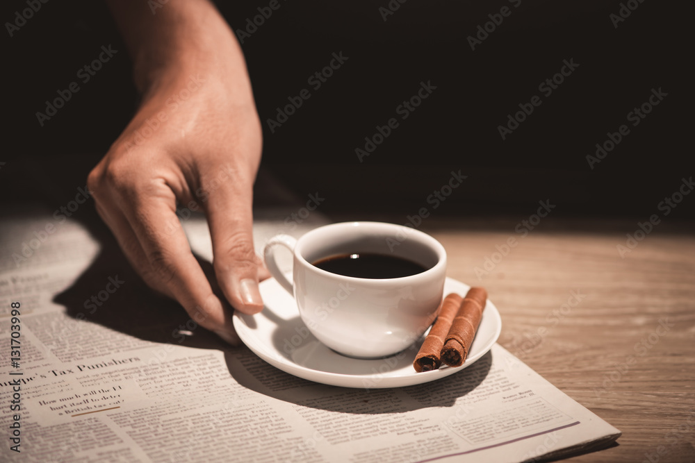 Male hands holding a cup of coffee over wooden table.