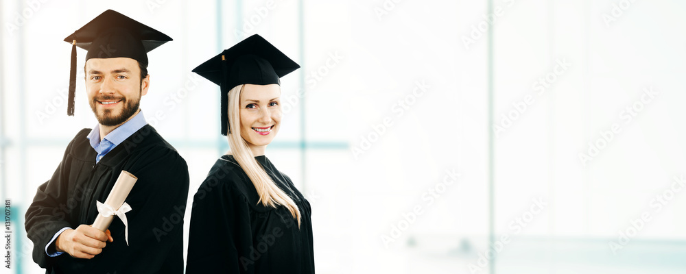 graduation - happy students wearing gown and cap. copy space