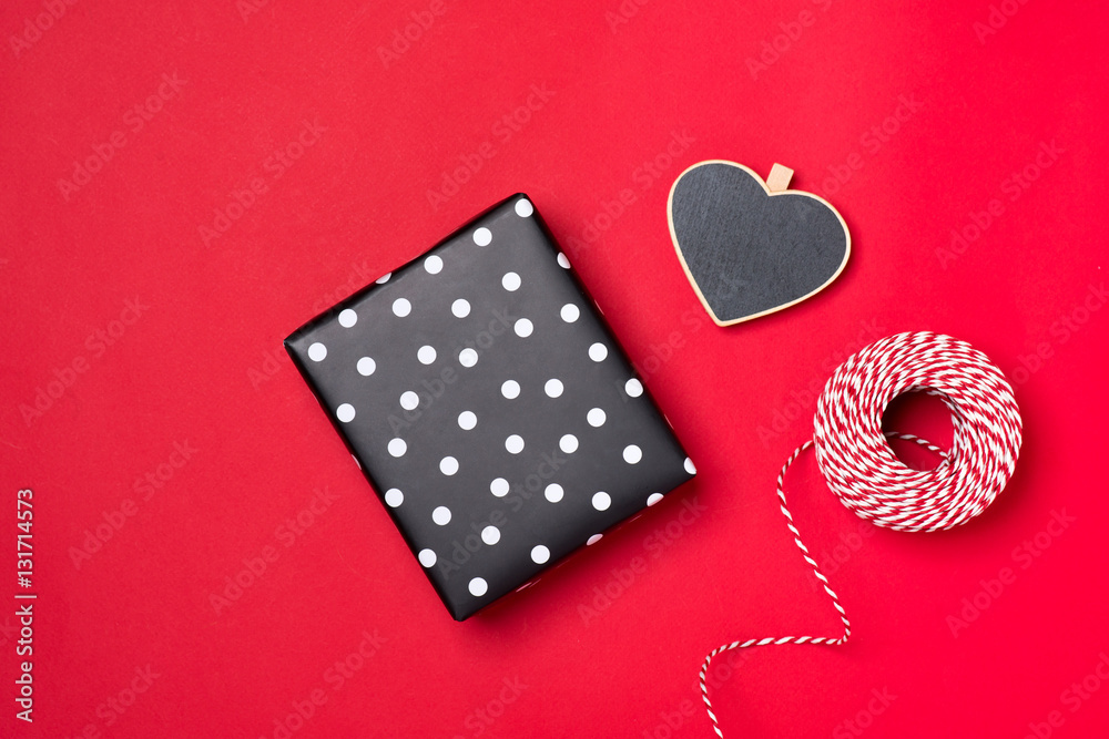 Handmade small gift box with heart symbol on red background.