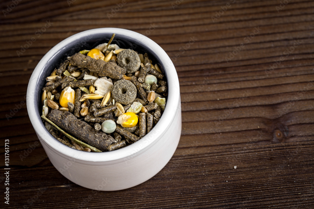 dry food for rodents in bowl wooden background