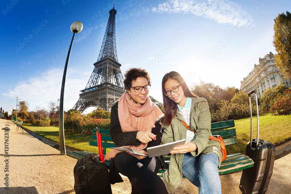 Two tourists sitting against the Eiffel Tower