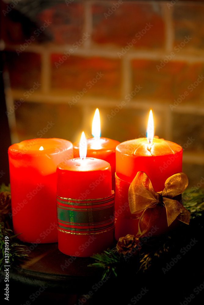 Four red candles with christmas decoration in atmospheric light. Moody. Authentic.