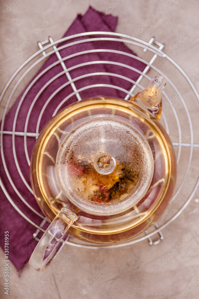 Glass teapot with tea on cooling rack. Concrete background. Top view.