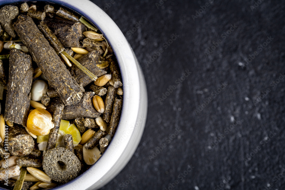 dry food for rodents in bowl dark background top view