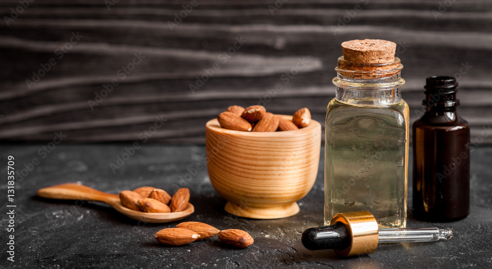 cosmetic almond oil in glass bottle on dark wooden background