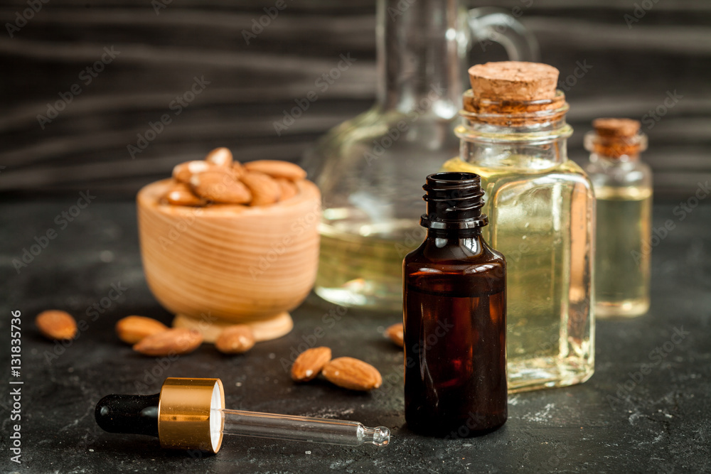 cosmetic almond oil in glass bottle on dark wooden background