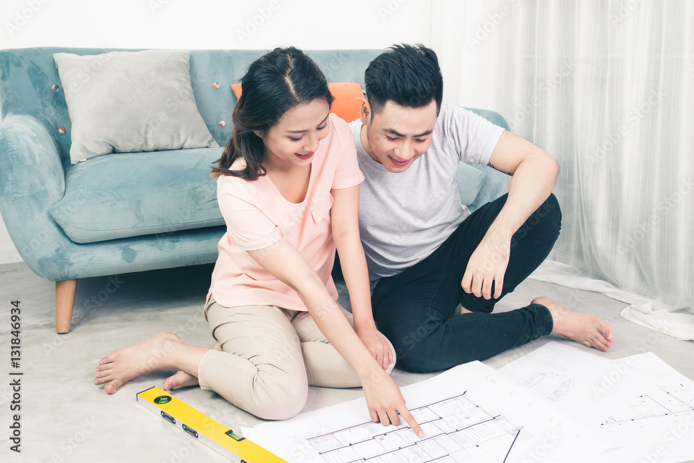 Attractive young asian adult couple looking at house plans.