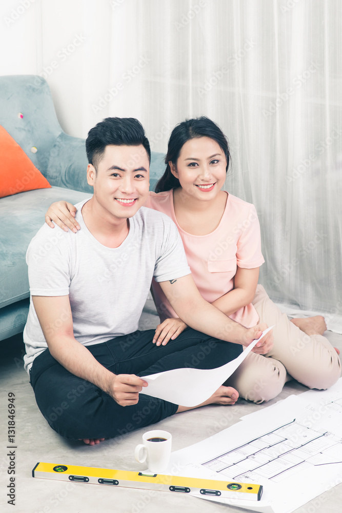 Attractive young asian adult couple looking at house plans.