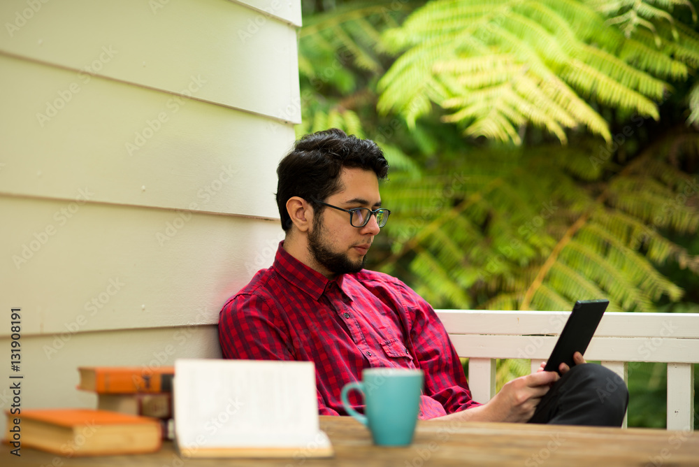 Young man with reader sitting outdoor