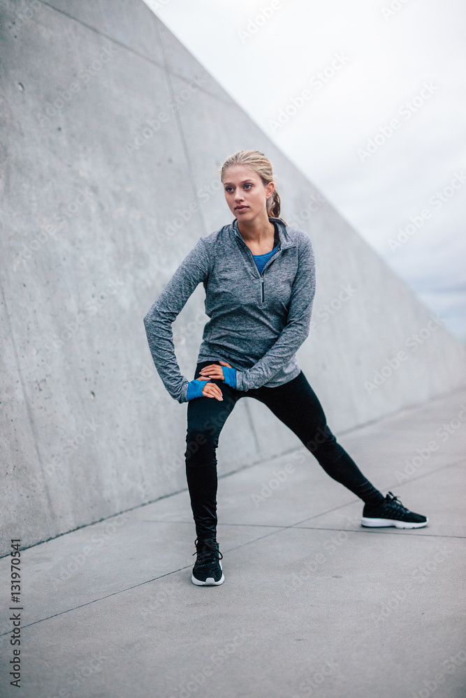 Female runner doing stretches in city