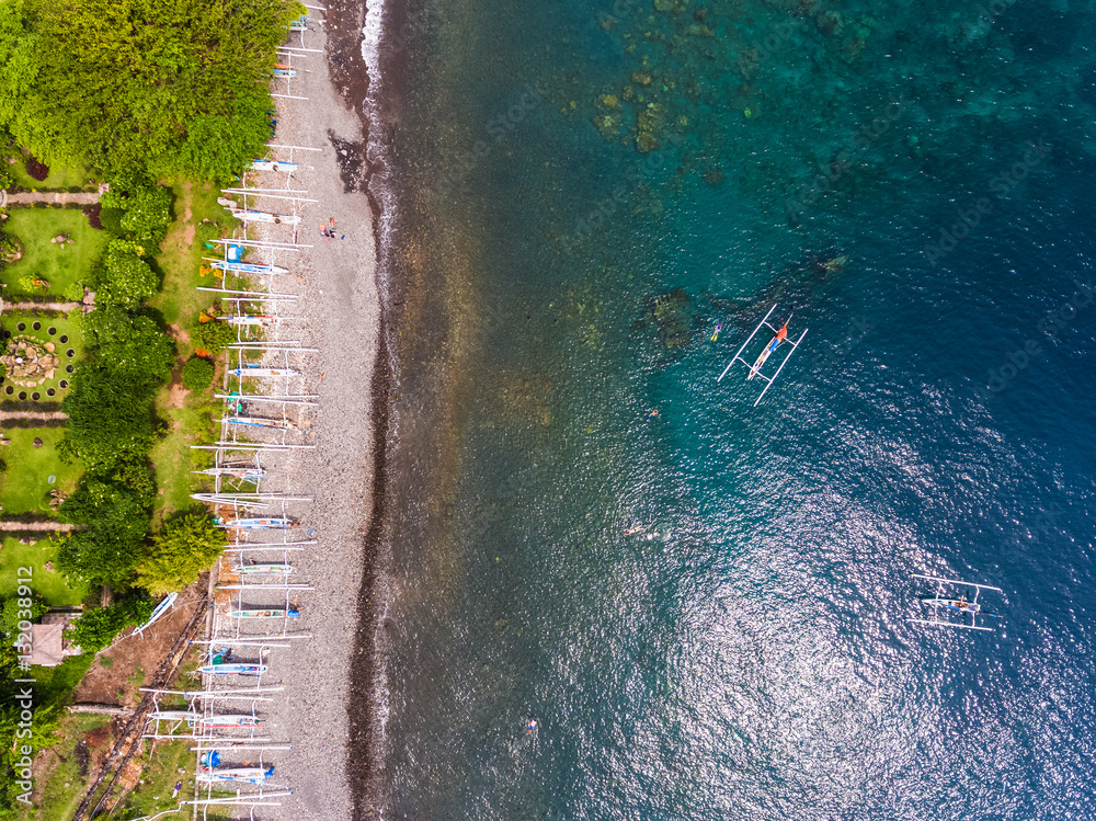 Aerial shot of Japanese ship wreck sunk near the coast. Traditional boats on the beach and green gar