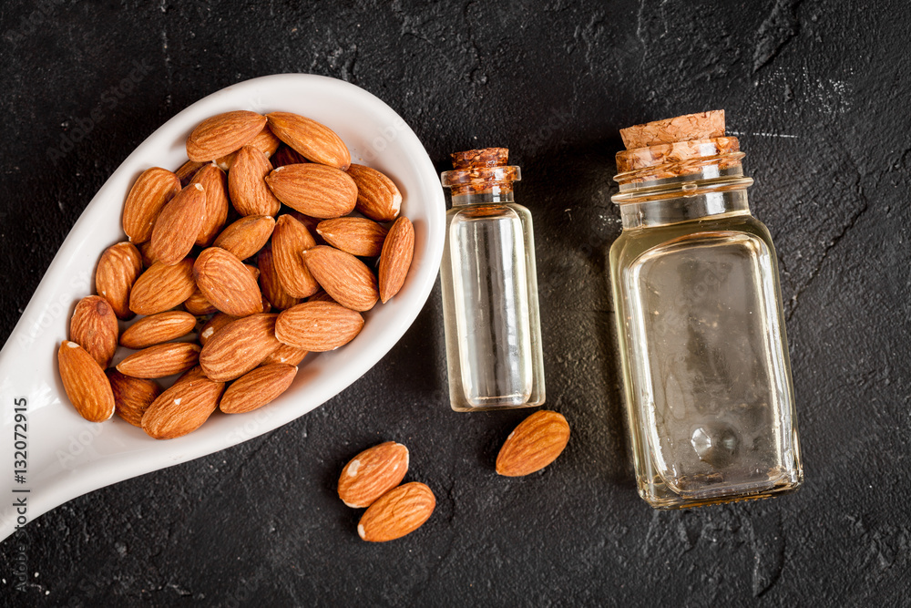 cosmetic almond oil in glass bottle on dark background