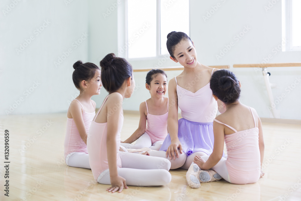 Young ballet instructor teaching girls in ballet studio