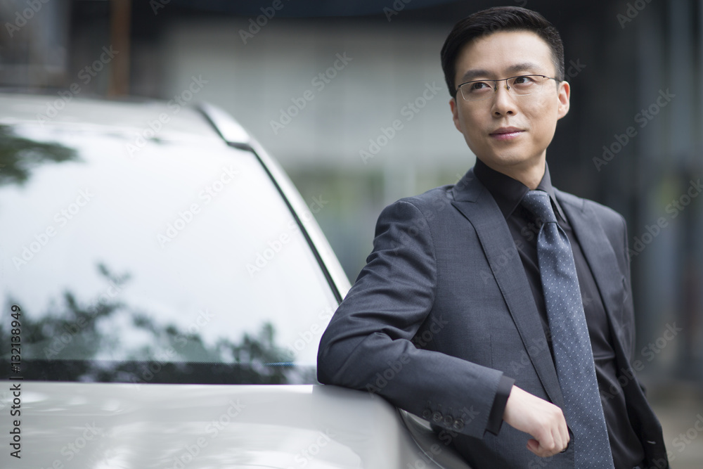 Mid adult businessman standing next to the car