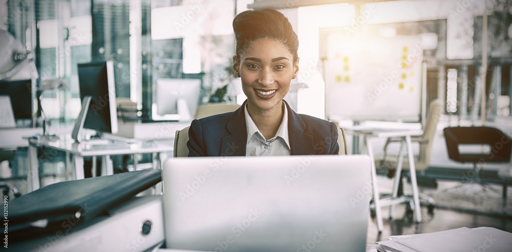 Portrait of smiling businesswoman by desk