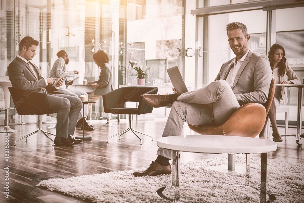 Smiling businessman using laptop in office