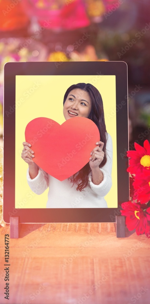 Composite image of smiling asian woman holding paper heart