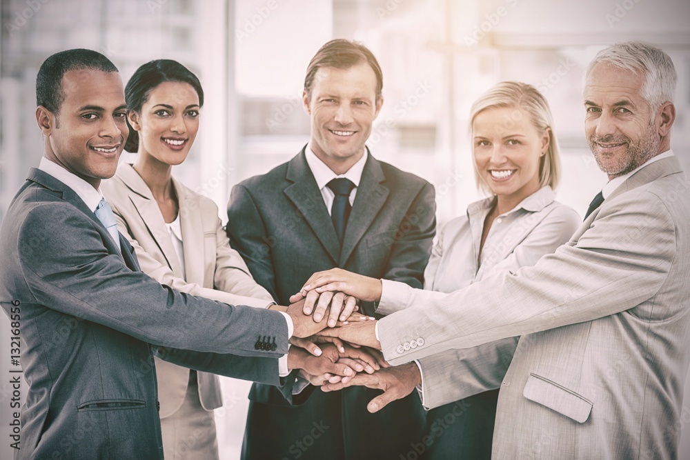 Group of smiling business people piling up their hands together