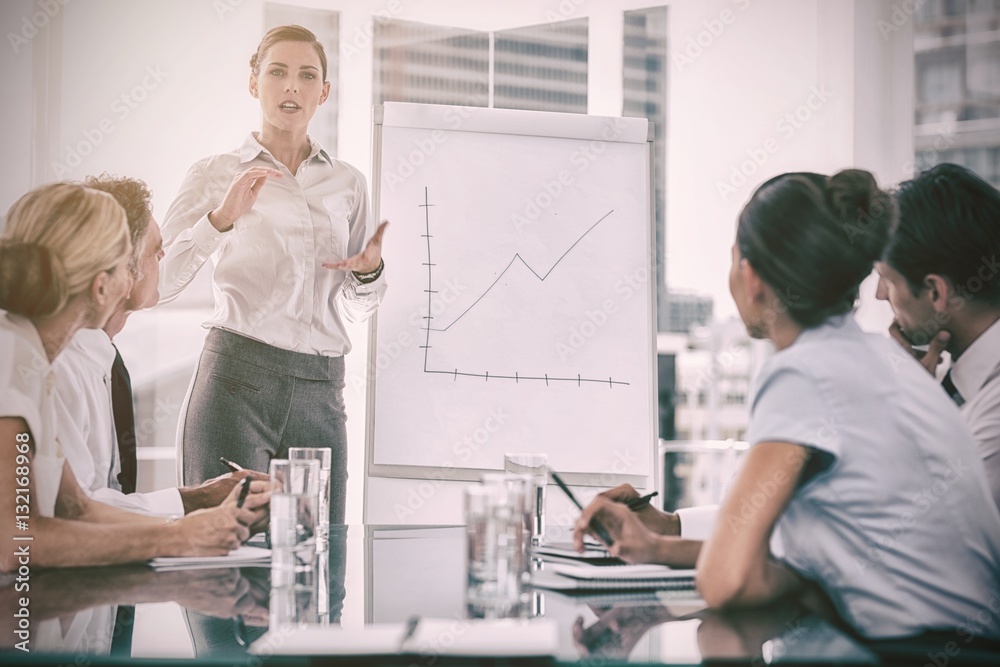 Businesswoman giving explication in front of a growing chart