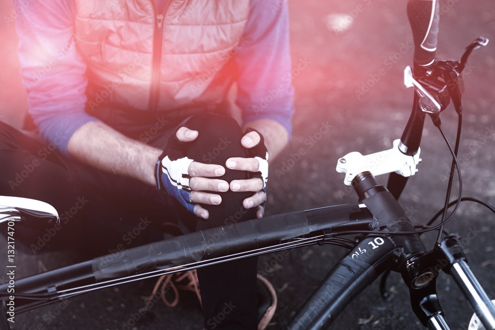 Midsection of male biker in pain holding his injured leg